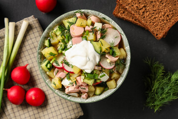 Composition with bowl of tasty okroshka, ingredients and bread on dark background