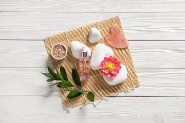 Obraz na płótnie Canvas Composition with bottle of essential oil, guasha tool, sea salt and spa stones on light wooden background