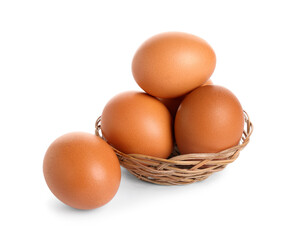 Wicker bowl with brown chicken eggs on white background