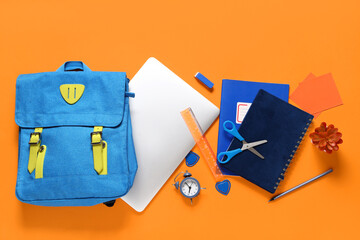 Composition with modern laptop and school supplies on orange background