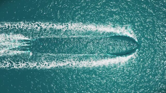 Cinematic aerial shot over the open ocean, featuring dynamic foam trails swirling around an invisible moving boat perfect for CGI integration or visual effects. 4K