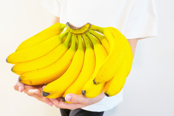 白背景に室内で子供が持つ大きな黄色いバナナの一房