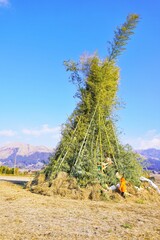 火がつけられる前のどんどやの大きなやぐらの裾に正月飾りを置く子ども、日本の正月の伝統文化、火祭り