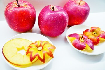 白バックに花の形に飾り切りされた林檎と輪切りで星形に型抜きされた赤い林檎