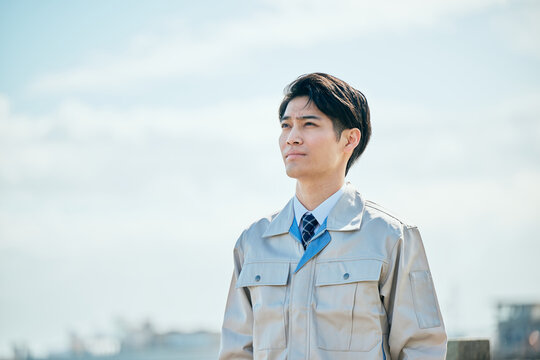 屋外で未来を見つめる作業服姿の男性