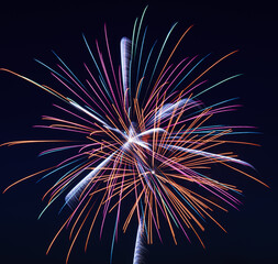 Vibrant fireworks exploding in the night sky, with streaks of red, blue, orange, and purple radiating outward, capturing the excitement and beauty of a festive celebration.