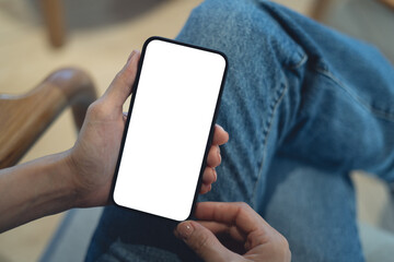 Mockup blank white screen mobile phone. Woman hand holding, using smartphone at coffee shop, template for mobile app design, social media marketing, close up