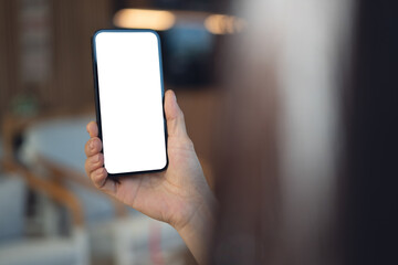 Mockup blank white screen mobile phone. Woman hand holding, using smartphone at coffee shop, template for mobile app design, social media marketing, close up