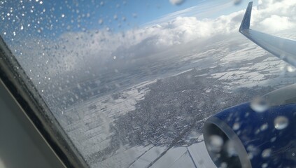Aerial view of snowy landscape, plane window, raindrops
