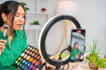 Influencer creating makeup tutorial video using ring light and smartphone