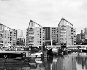 Naklejka premium Canal boats moored in front of modern apartment buildings in london's limehouse basin