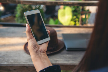 Close up woman hands using smartphone online video call texting message. Female hand touch empty screen cellphone smart tablet on hands using mobile app home office. Asian woman sitting wooden table