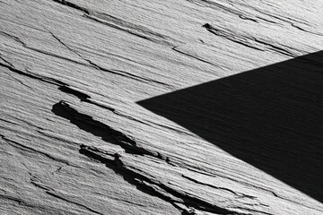 Abstract grayscale image of layered rock face with a triangular shadow