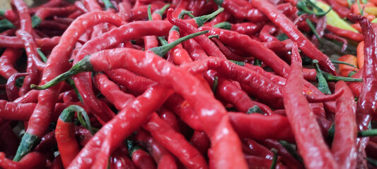 Overhead close-up shot of a pile of red chili peppers with a few yellow, pile of chilies in traditional container, high quality photo as a promotional tool for spicy food, isolated on white background