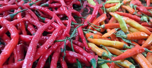 Overhead close-up shot of a pile of red chili peppers with a few yellow, pile of chilies in traditional container, high quality photo as a promotional tool for spicy food, isolated on white background