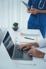 Healthcare and Tech: A doctor sits attentively, engrossed in a digital analysis on a sleek laptop, as a colleague reviews information.