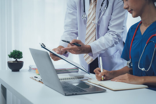 Consulting on Care: A doctor and a nurse are focused on examining medical information, with their gaze centered on a shared medical record, and taking notes.