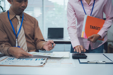 Teamwork on Target: A focused business pair collaborating in the office, analyzing data and crunching numbers, as they strategize to reach their TARGET goal.