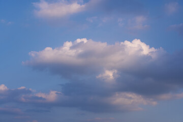 Soft white and dark clouds drifting across a deep blue sky. Peaceful, natural cloudscape with a gentle, moody atmosphere.