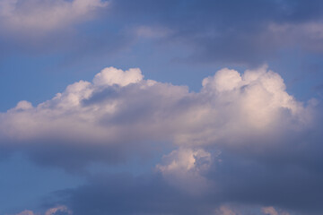 Obraz premium Soft white and dark clouds drifting across a deep blue sky. Peaceful, natural cloudscape with a gentle, moody atmosphere.