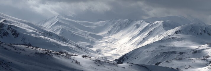 Serene Snowy Mountain Landscape with Dramatic Cloudy Sky and Majestic Peaks Illuminated by Soft Winter Light
