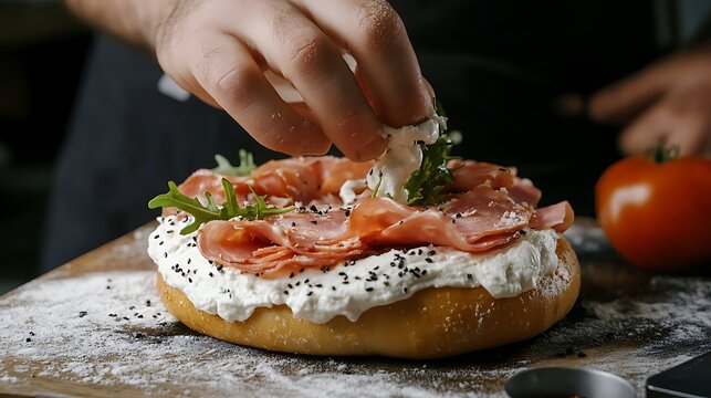 Spreading cream cheese on the bagel before adding ham