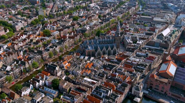 Crisp 4K aerial over Amsterdam&rsquo;s historic center, with the Gothic Oude Kerk framed by canals, gabled houses and bridges an iconic Dutch cityscape alive with summer light.
