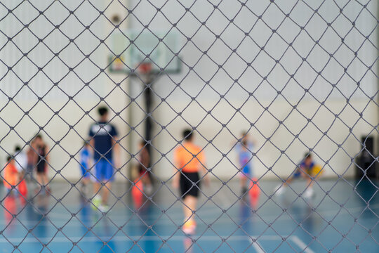 blur basketball court by rope mesh net fence focus with many youth children or kid learning training dribbling shooting ball to playing basketball with coach and basketball hoop for sport exercise