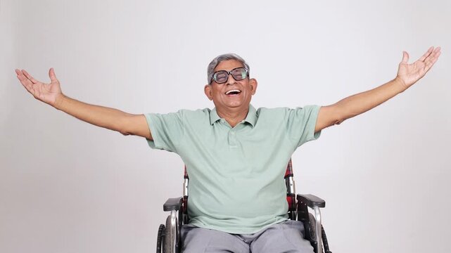Joyful Retired senior indian man on wheelchair laughing with open arms. Carefree elderly gray hair male wearing eye wear looking at camera. Retirement life. 4k