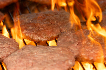 Raw hamburger patties on a hot grill