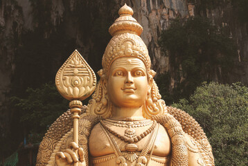 Golden statue of Hindu god Murugan at Batu Caves, Malaysia. Hinduism, temple deity, Asian religion, pilgrimage site, sacred sculpture.