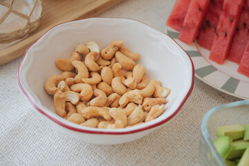 Cashews in a bowl next to fresh fruit platter