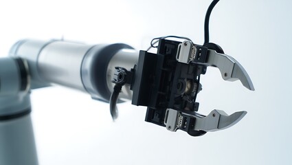 Close-up of a silver industrial robotic gripper arm with open jaws on a bright background, symbolizing precision and automation