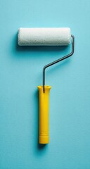 A paint roller, white and fluffy, rests on a bright teal surface.  The handle is a vibrant yellow