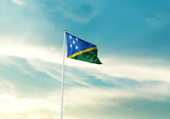 Solomon Islands flag is waving on a tall flagpole among the clouds. Solomon Islands national flag for independence day.