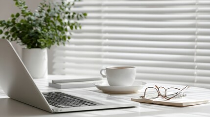 modern minimalist workspace, sleek laptop on white desk, coffee cup and saucer, eyeglasses and notepad neatly arranged, small green plant, soft natural lighting through window blinds