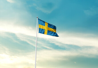 Sweden flag is waving on a tall flagpole among the clouds. Sweden national flag for independence day.
