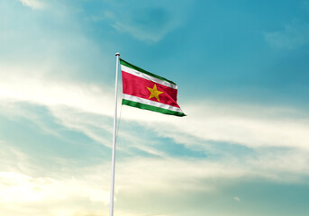 Suriname flag is waving on a tall flagpole among the clouds. Suriname national flag for...