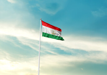 Tajikistan flag is waving on a tall flagpole among the clouds. Tajikistan national flag for independence day.