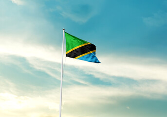 Tanzania flag is waving on a tall flagpole among the clouds. Tanzania national flag for independence day.