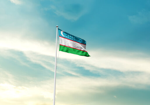 Uzbekistan flag is waving on a tall flagpole among the clouds. Uzbekistan national flag for independence day. - Powered by Adobe