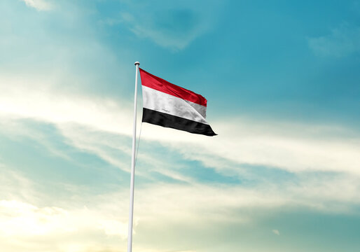 Yemen flag is waving on a tall flagpole among the clouds. Yemen national flag for independence day. - Powered by Adobe