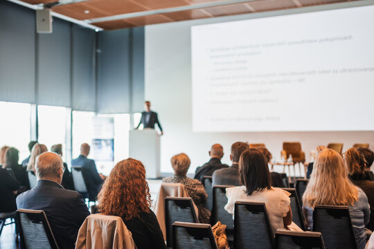 Speaker giving a talk in conference hall at business event. Rear view of unrecognizable people in audience at the conference hall. Business and entrepreneurship concept
