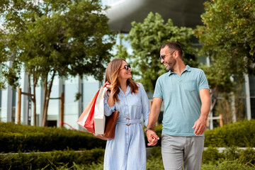 Couple enjoys a sunny day while shopping together in an urban outdoor plaza surrounded by beautiful greenery © BGStock72