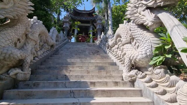 Climbing stone stairs. Stone dragon, winding, on the steps of Buddhist temple. Sculpture, water flows from mouth of stone dragon. Buddha Amitabha Temple, Nha Trang, Vietnam