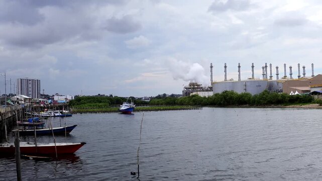 Pertamina Oil and gas refinery industry, equipment details Steel oil pipelines with valves from large oil storage tanks and mangrove conservation as foreground.