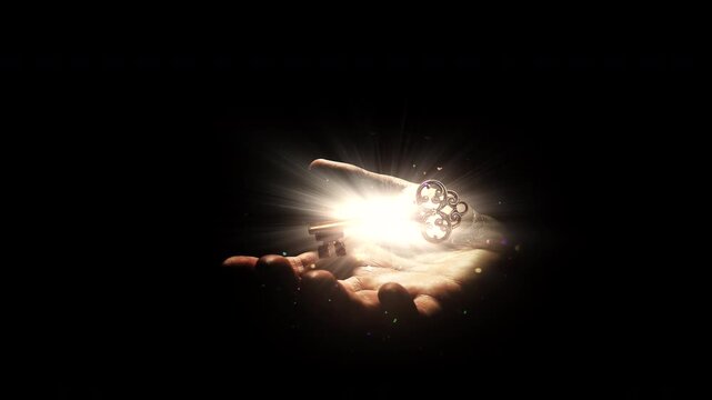 Magic ancient golden key with bright glow from light rays in magic flying dust slowly hovers over human palm isolated on black. Idea of awareness, open mind, awakening. Conceptual 4k slow motion video