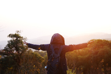 Asian young woman backpack spread arms freely in life and standing with wildflower and beautiful landscape of valley Doi Luang Chiang Dao mountain, Chiang Mai Province of Thailand