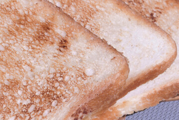 Toasted bread slices displayed on a textured surface, showcasing a golden brown color and crunchy texture