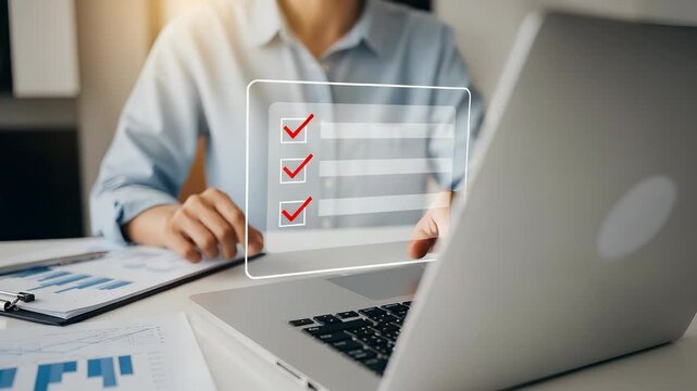 Woman Checks Virtual Checklist Overlayed on Laptop in Bright Office Space with Charts and Graphs for Task Management and Business Goals